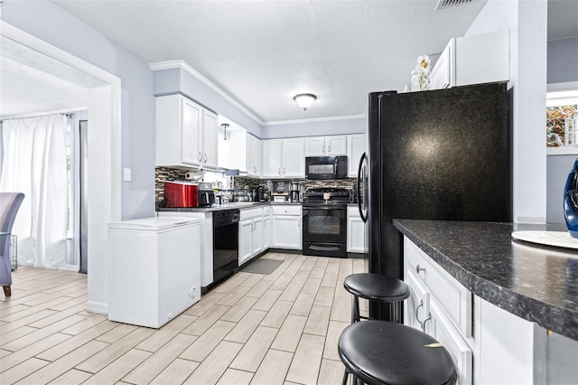 kitchen featuring black appliances, tasteful backsplash, and white cabinetry