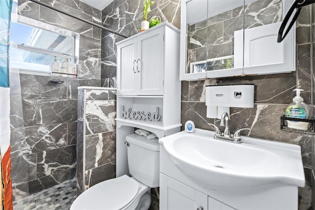 bathroom featuring tasteful backsplash, tiled shower, toilet, vanity, and tile walls