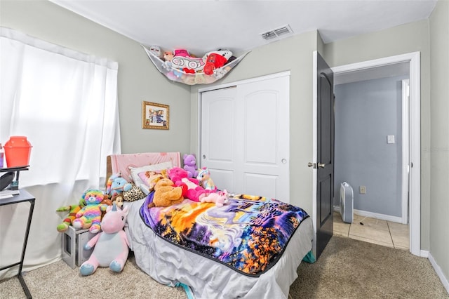 bedroom featuring baseboards, visible vents, tile patterned flooring, carpet floors, and a closet