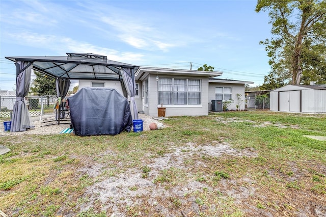 back of property with an outbuilding, concrete block siding, a storage shed, central AC unit, and fence