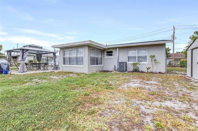 back of property featuring central air condition unit, fence, a gazebo, a lawn, and a patio area