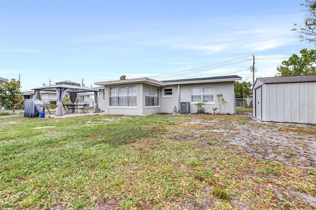 rear view of property with central AC, an outdoor structure, a yard, a gazebo, and a shed