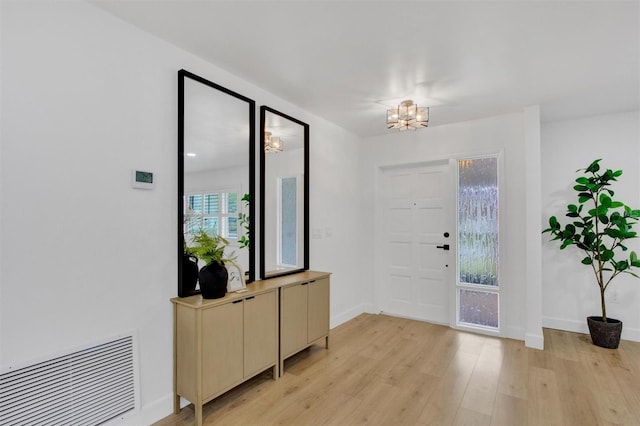 entrance foyer featuring a chandelier, light wood-style flooring, visible vents, and baseboards