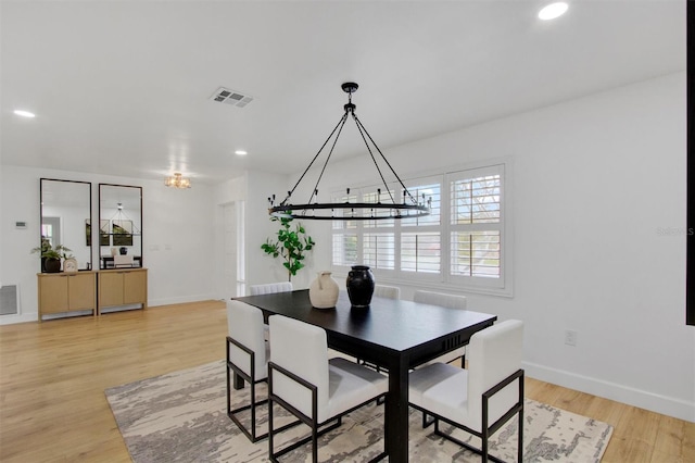 dining space with a chandelier, light wood finished floors, visible vents, and baseboards