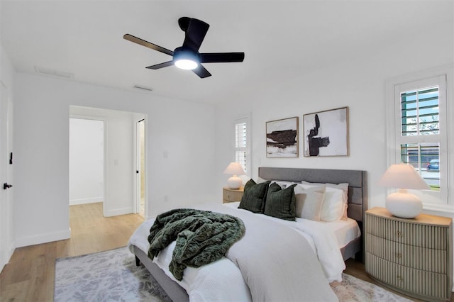 bedroom featuring visible vents, wood finished floors, a ceiling fan, and baseboards