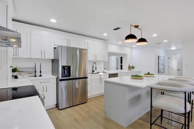 kitchen with appliances with stainless steel finishes, visible vents, light wood-style flooring, and white cabinetry