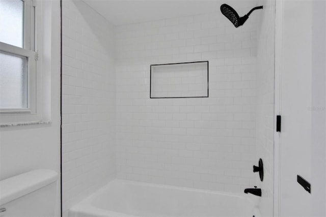 bathroom featuring washtub / shower combination, toilet, and a healthy amount of sunlight