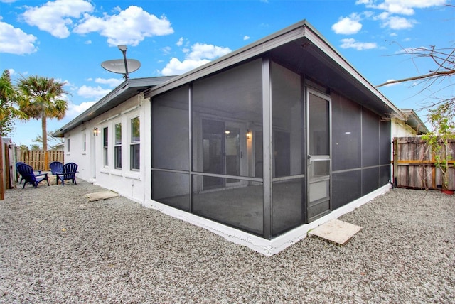 view of side of property with a sunroom and fence