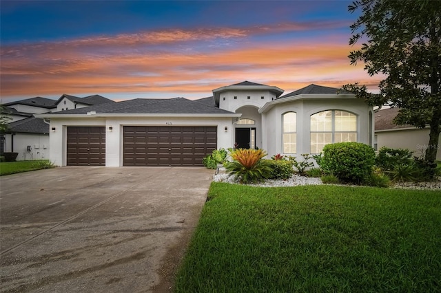 view of front facade with a front yard, driveway, an attached garage, and stucco siding