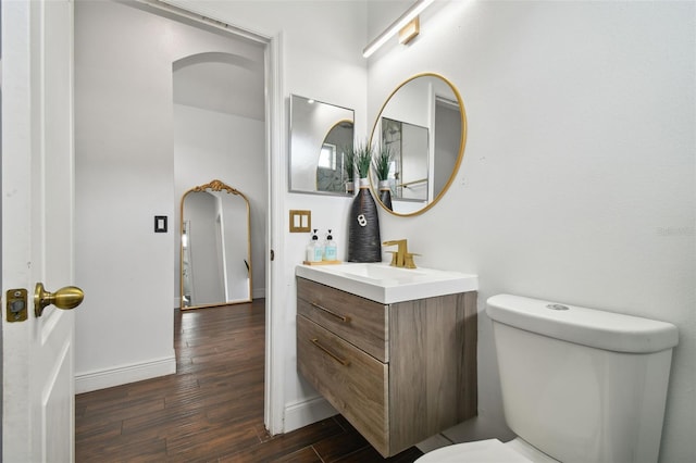 bathroom featuring toilet, baseboards, wood finished floors, and vanity