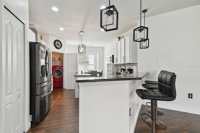 kitchen with tasteful backsplash, dark wood finished floors, a peninsula, stainless steel appliances, and separate washer and dryer