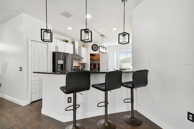 kitchen featuring dark countertops, stainless steel fridge, a kitchen bar, and a sink