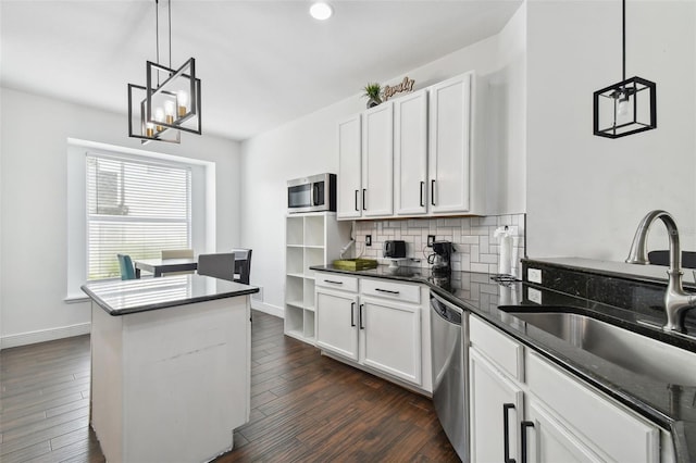 kitchen with dark wood finished floors, tasteful backsplash, appliances with stainless steel finishes, white cabinetry, and a sink