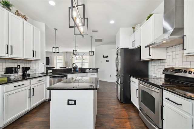 kitchen featuring a peninsula, dark wood-type flooring, visible vents, appliances with stainless steel finishes, and wall chimney exhaust hood