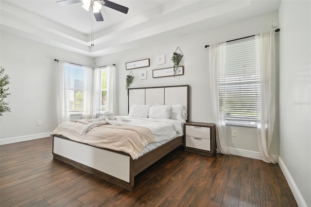 bedroom with baseboards, a tray ceiling, ceiling fan, and dark wood-style flooring