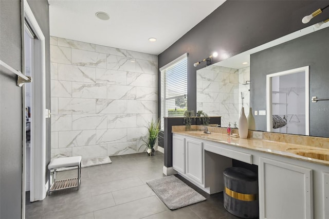 full bathroom with double vanity, a sink, a walk in shower, and tile walls