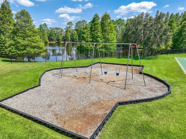 community playground featuring a water view, fence, and a lawn