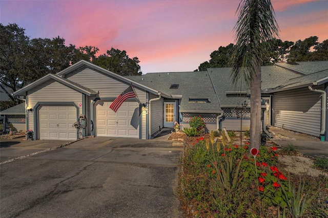 view of front of property featuring concrete driveway, a garage, and a shingled roof