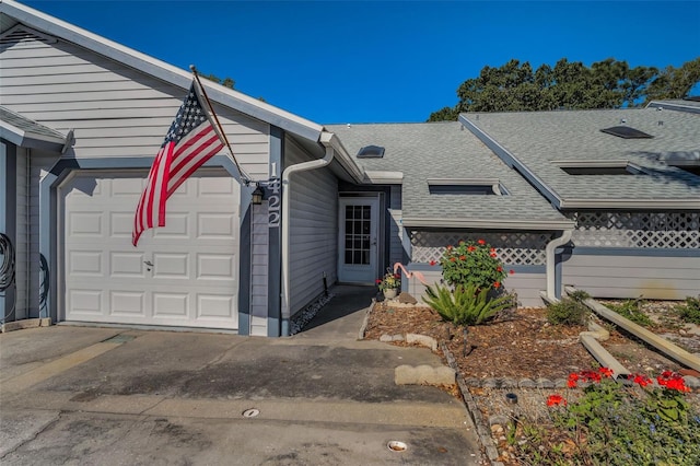 ranch-style home featuring driveway, a shingled roof, and a garage