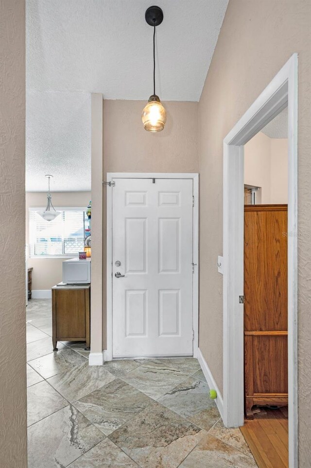 foyer entrance featuring baseboards and a textured ceiling