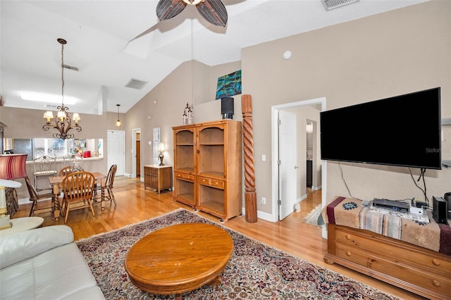 living area with visible vents, ceiling fan with notable chandelier, light wood-style floors, and lofted ceiling