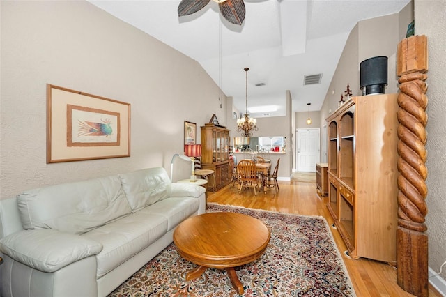 living room featuring light wood finished floors, visible vents, lofted ceiling, and a ceiling fan