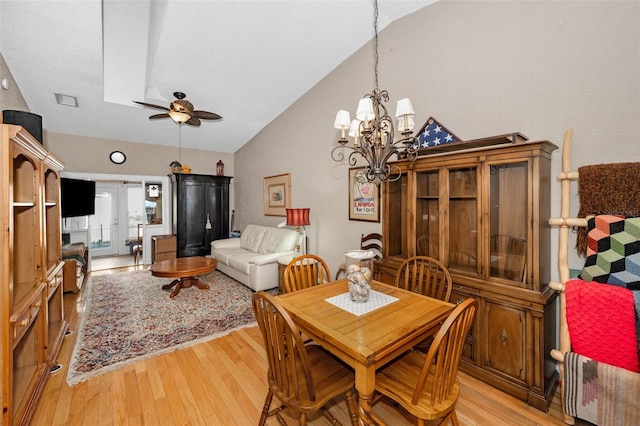 dining space with light wood-type flooring, high vaulted ceiling, visible vents, and ceiling fan with notable chandelier