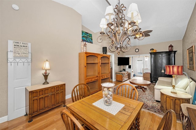 dining area with lofted ceiling, baseboards, light wood-style floors, and an inviting chandelier