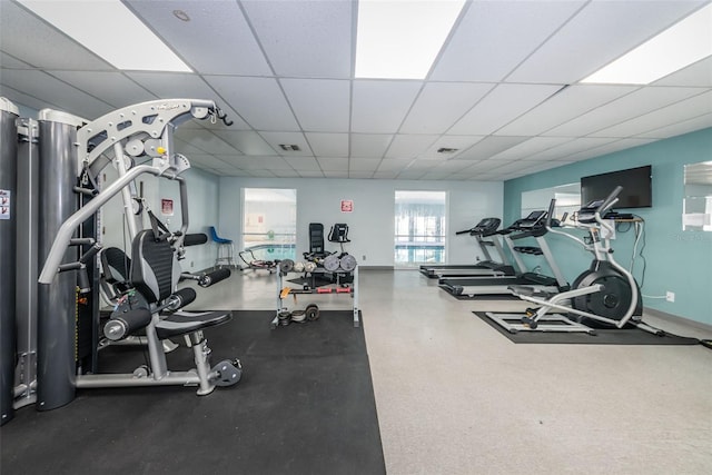 exercise room featuring a paneled ceiling, visible vents, and baseboards