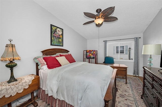 bedroom with lofted ceiling, a textured ceiling, light wood-style floors, and ceiling fan