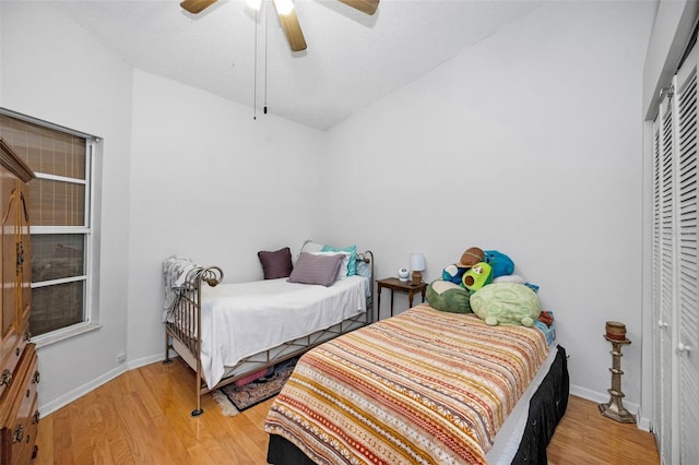 bedroom with baseboards, light wood-style floors, and lofted ceiling