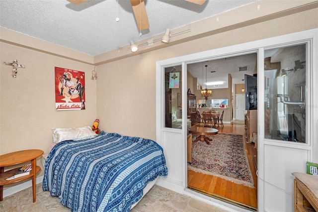 bedroom featuring visible vents, ceiling fan with notable chandelier, baseboards, and a textured ceiling