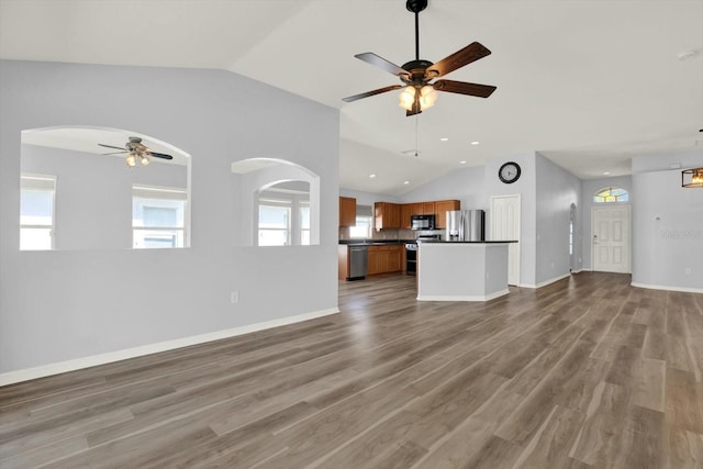 unfurnished living room featuring ceiling fan, wood finished floors, plenty of natural light, and lofted ceiling