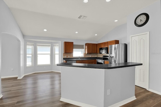 kitchen featuring arched walkways, dark countertops, visible vents, appliances with stainless steel finishes, and dark wood-type flooring