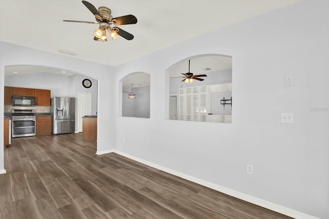 interior space with visible vents, dark wood-type flooring, a ceiling fan, vaulted ceiling, and baseboards