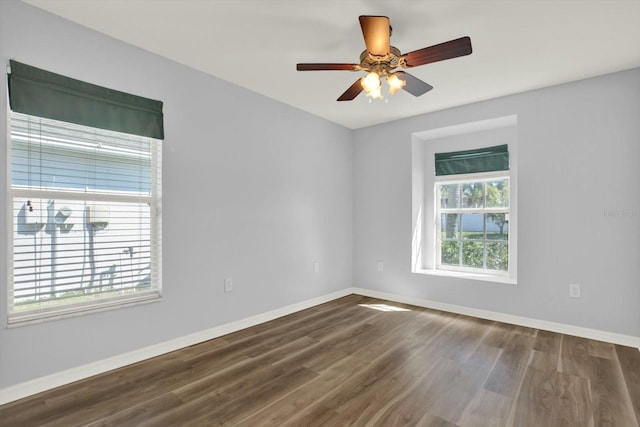 spare room featuring ceiling fan, dark wood-type flooring, and baseboards