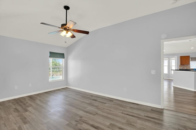 spare room featuring baseboards, wood finished floors, and a healthy amount of sunlight