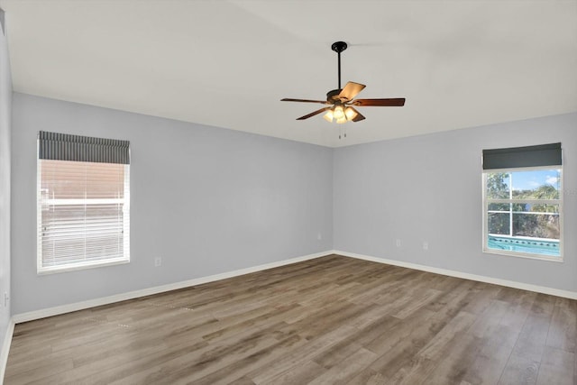 empty room featuring a ceiling fan, baseboards, and wood finished floors