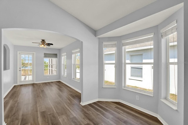 unfurnished sunroom with a ceiling fan, lofted ceiling, and arched walkways