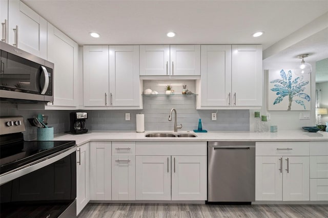 kitchen featuring a sink, white cabinets, light countertops, appliances with stainless steel finishes, and open shelves