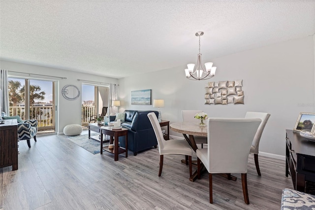 dining room with a textured ceiling, baseboards, wood finished floors, and an inviting chandelier