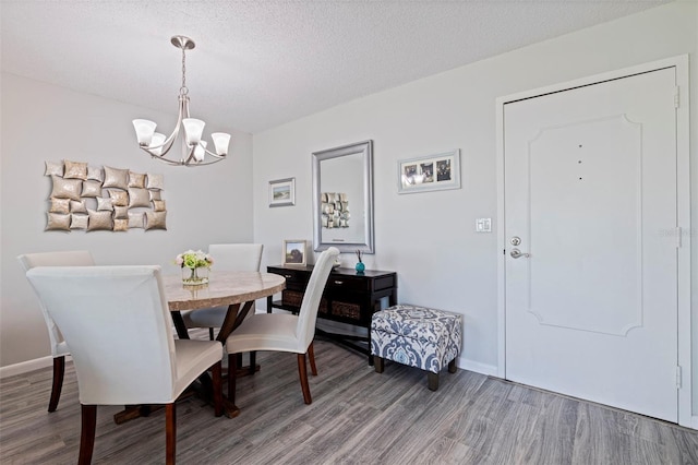 dining room with baseboards, a textured ceiling, a chandelier, and wood finished floors