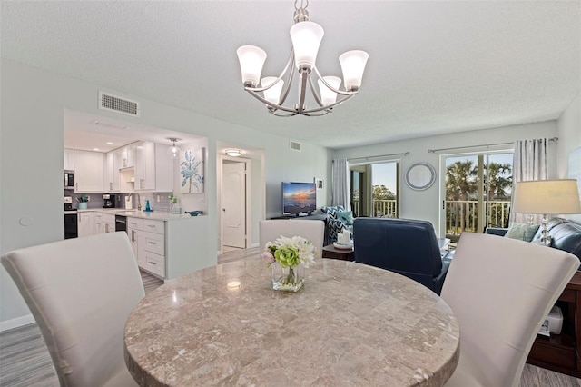 dining space with an inviting chandelier, visible vents, and a textured ceiling