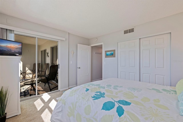 carpeted bedroom featuring a closet, visible vents, a textured ceiling, and baseboards