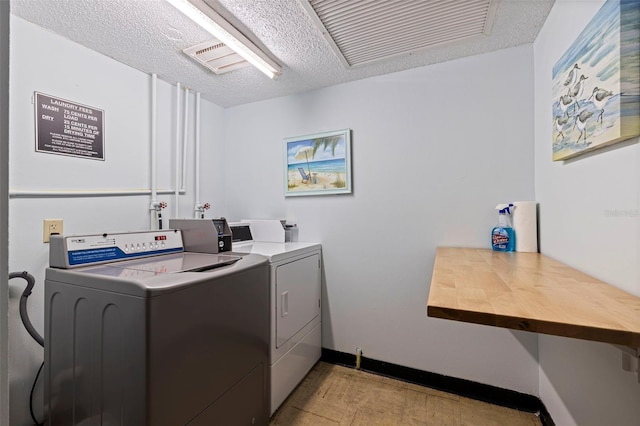 shared laundry area with baseboards, a textured ceiling, and washing machine and clothes dryer