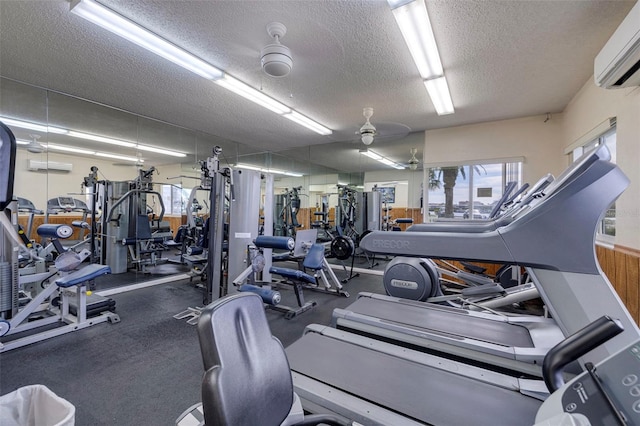 gym with a textured ceiling, an AC wall unit, and ceiling fan