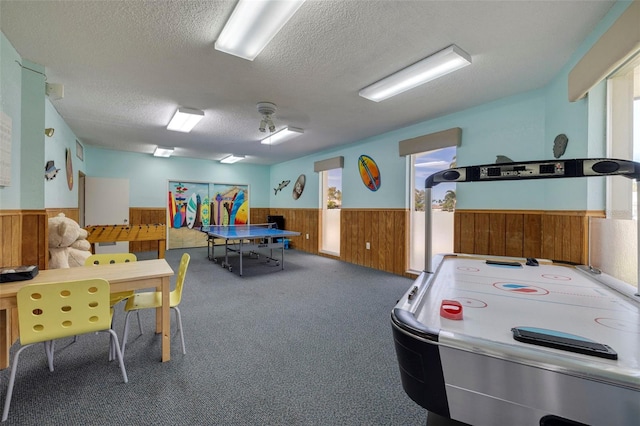 rec room with carpet floors, wood walls, a textured ceiling, and wainscoting