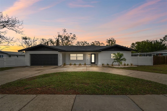 view of front facade with an attached garage, brick siding, fence, concrete driveway, and a front yard