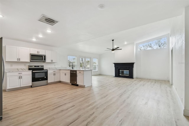 kitchen with visible vents, ceiling fan, a fireplace with flush hearth, stainless steel appliances, and light countertops