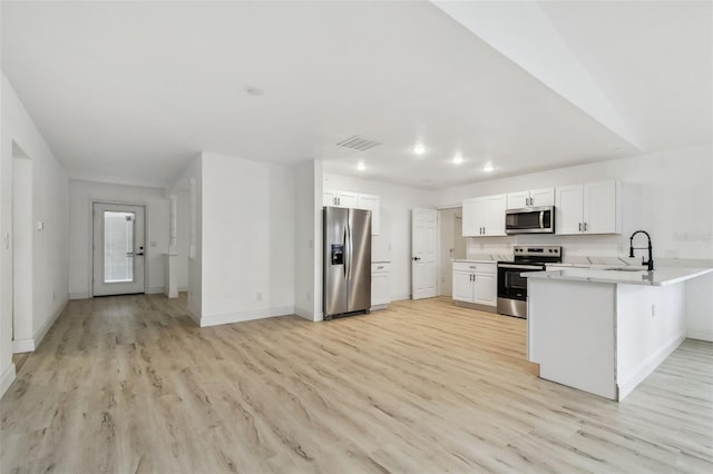 kitchen with light wood finished floors, visible vents, appliances with stainless steel finishes, a peninsula, and a sink